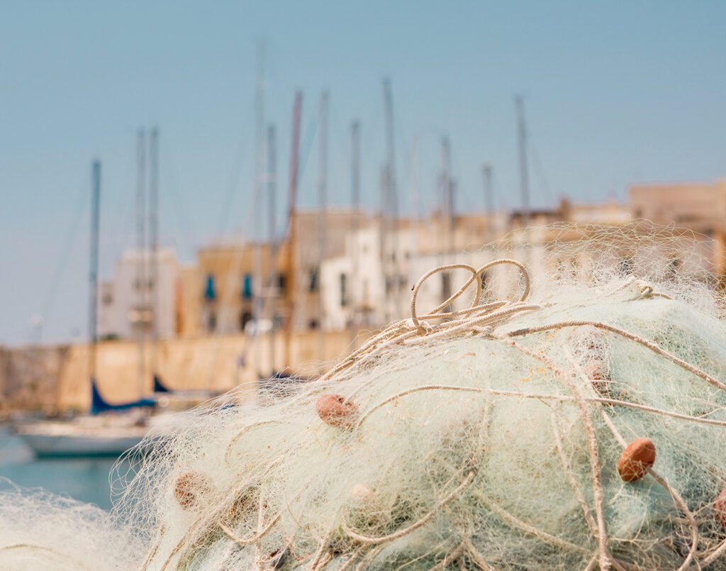 fishing nets with boats in the background in gallipoli italy under the summer sun