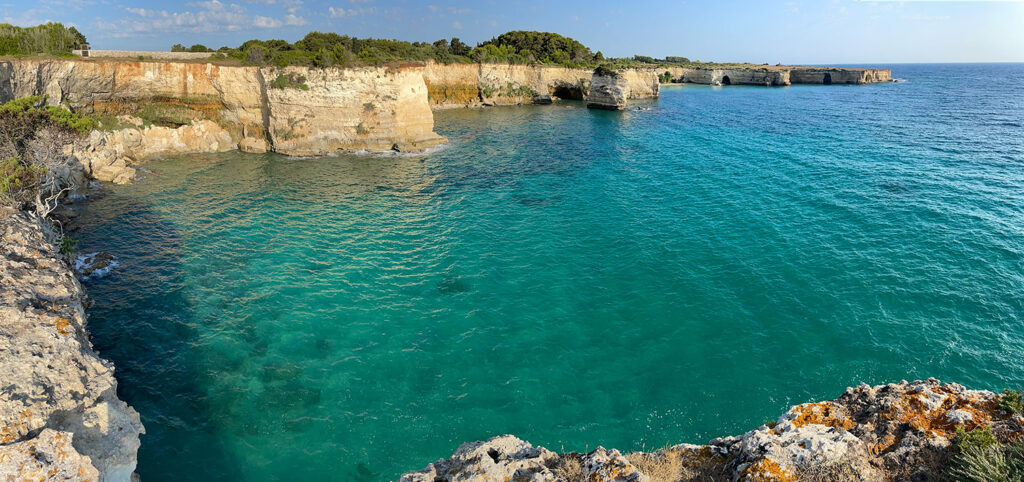 clear neon blue waters along the cliffs leading to Mulino d'Acqua beach in Puglia